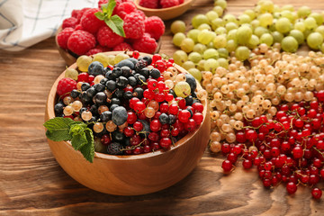 Bowl with fresh ripe berries on wooden table