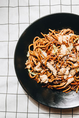 Meat with noodles in black plate, Asian cuisine, chopsticks