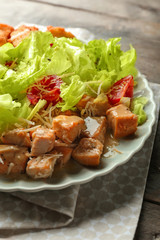 Plate with tasty Caesar salad on wooden table, closeup