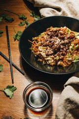 Meat with noodles in black plate, Asian cuisine, chopsticks
