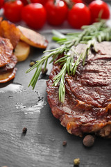 Slate plate with tasty grilled meat and herbs, closeup