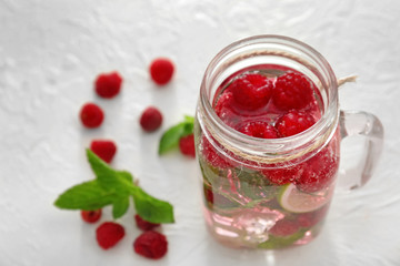 Mason jar of fresh raspberry mojito on white table