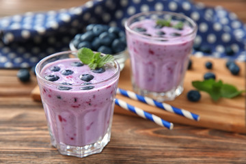 Glasses of tasty blueberry smoothie on wooden table