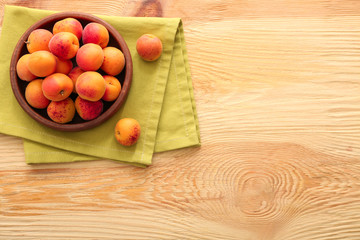 Bowl with fresh apricots on wooden table