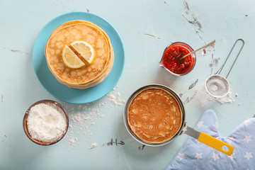 Delicious thin pancakes with jam and flour on light table