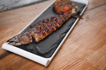Slate plate with delicious fried fish on wooden table