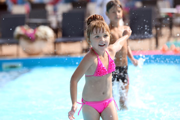 Cute girl playing in swimming pool on summer day