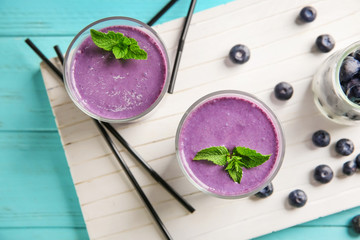 Glasses with tasty blueberry smoothie on color wooden table