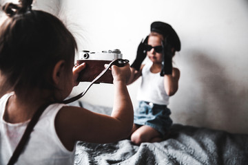 Two little girls taking a picture of each other. little women of fashion