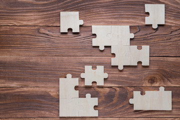 Incomplete wooden puzzles on brown wooden desk, top view, flat lay.