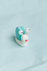 Creative snail decoration with delicious macaroon on blue table