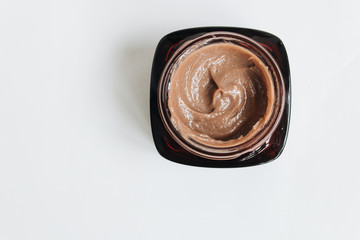 Chocolate cream in small jar on white background