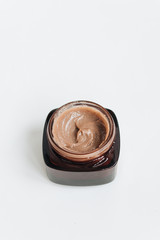 Chocolate cream in small jar on white background