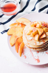Stack of delicious homemade pancakes with sauce and sliced appl