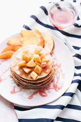 Stack of delicious homemade pancakes with sauce and sliced appl