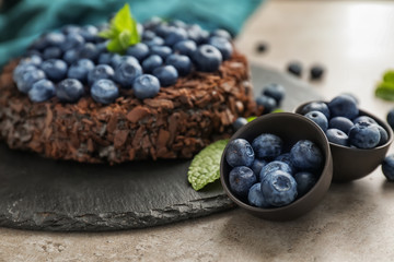 Bowls with blueberries and chocolate cake on grey table