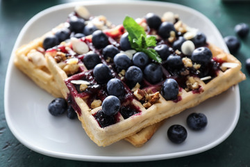 Delicious waffles with blueberries and jam on plate