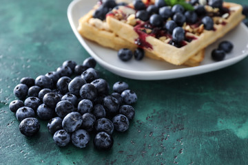Pile of ripe blueberries with waffles on table