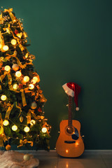 Beautiful decorated Christmas tree with guitar near color wall indoors
