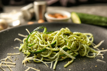 Spaghetti with zucchini and pesto sauce on plate, closeup