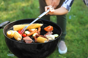 People cooking tasty food on barbecue grill outdoors, closeup