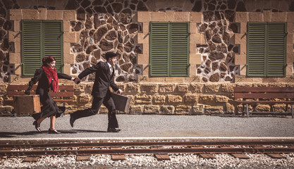 Young couple with vintage suitcase on the trainlines ready for a journey.