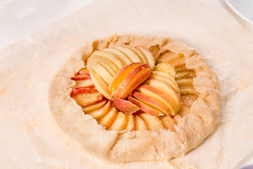 Raw peach galette on parchment paper