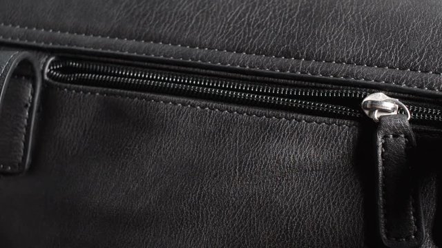 Young woman opening the zipper of a ladies handbag. Closeup of female hand.