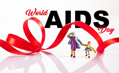 miniatures peoples: a group of people pose in front of a red ribbon to prevent against me AIDS