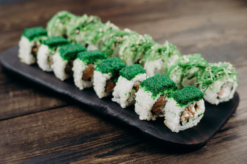 Sushi restaurant menu, Japanese food, gourmet meals. Rolls with smoked tuna and philadelphia cheese on wooden tray, close up