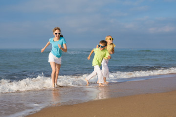 Three happy children running on the beach at the day time.