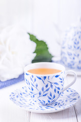 Porcelain cup of green tea and white hydrangea on a light wooden background. Free space