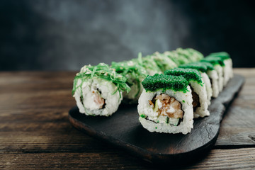 Japanese restaurant menu photo, traditional cuisine, delicious seafood, food art.  Appetizing maki sushi rolls with smoked tuna and philadelphia cheese on wooden tray, close up