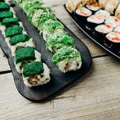Japanese cuisine, professional culinary, seafood, restaurant menu, food photo art. Delicious maki sushi rolls with assorted fillings set served on wooden table