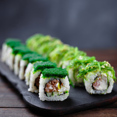 Japanese restaurant menu photo, traditional cuisine, delicious seafood, food art.  Appetizing maki sushi rolls with smoked tuna and philadelphia cheese on wooden tray, close up