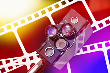 Old retro movie camera on background of perforation film