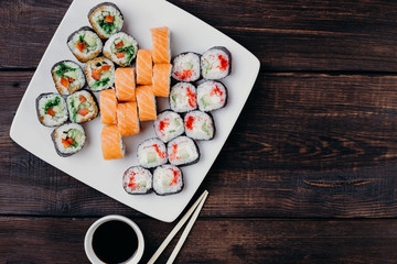 Food art, traditional  japanese seafood, restaurant menu photo. Tasty great colorful set of fresh sushi maki rolls with salmon, tuna and avocado served on white porcelain pate, flat lay