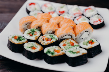 Food art, traditional  japanese seafood, restaurant menu photo. Tasty great colorful set of fresh sushi maki rolls with salmon, tuna and avocado served on white porcelain pate