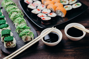 Japanese food, dinner at restaurant, traditional cuisine. Variety of tasty multicolored sushi rolls, selective focus