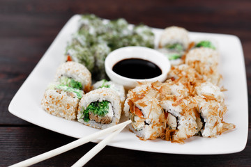 Japanese restaurant, traditional cuisine, menu. Appetizing set of sushi rolls served on porcelain plate served with chopsticks and sauce, selective focus