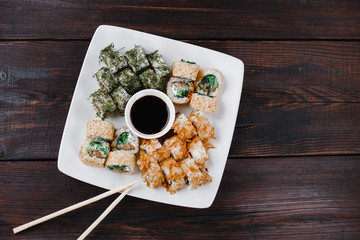 Fototapeta na wymiar Japanese restaurant, sushi plate. Appetizing seafood maki rolls set on white plate with sauce and chopsticks, copy space
