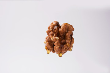 Golden walnut oil drop dripping fromnwhole Akrod/akhrot dry fruit, flying in the air isolated