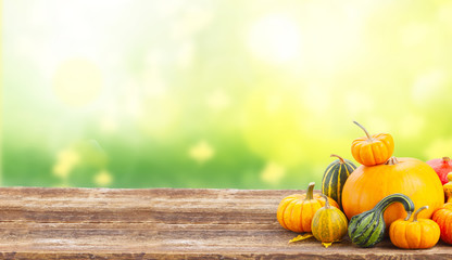 pile of orange pumpkins with fall leaves on wooden table over fall background banner