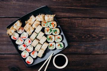 Restaurant menu, Japanese food art.  Appetizing sushi set served on black plate with sauce and chopsticks, copy space