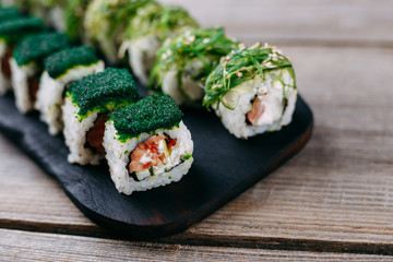Japanese restaurant menu, professional culinary, delicious and beautiful food. Tasty appetizing sushi roll with tuna, covered with calf caviar and chuka seaweed, close up
