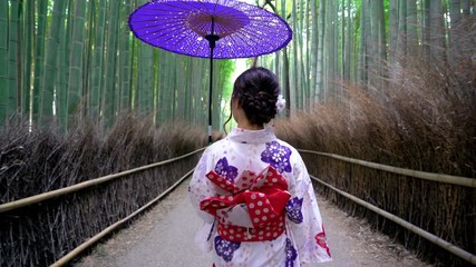 Asian woman wearing japanese traditional kimono at Bamboo Forest in Kyoto, Japan.
