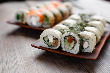 Japanese cuisine, professional culinary, seafood, restaurant menu, food photo art. Delicious maki sushi rolls with assorted fillings set served on wooden table