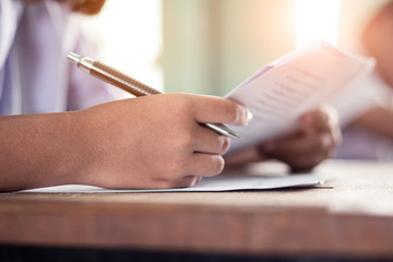 Close up Students writing and reading exam answer sheets exercises in classroom of school with...