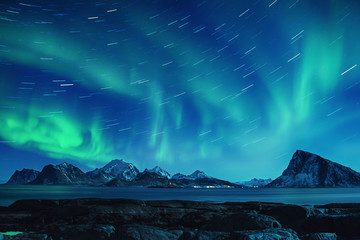 Northern Lights, Aurora Borealis shining green in night starry sky with star tracks at winter...