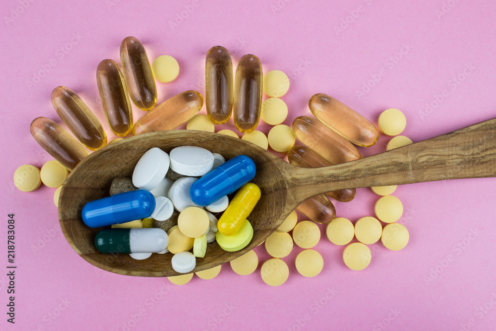 Wall mural Capsules and tablets on wooden spoon. Medicine pharmaceutical theme. 